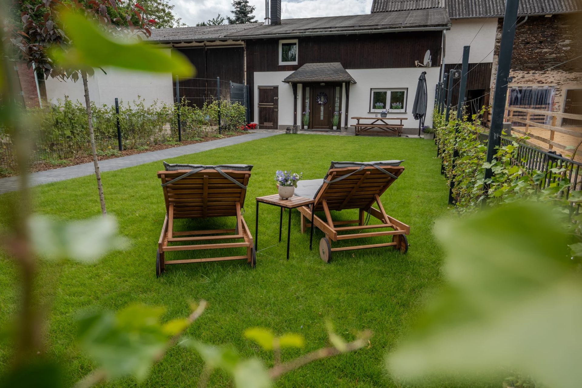 Sonnenliegen im Garten mit Blick auf den Innenhof und Stall